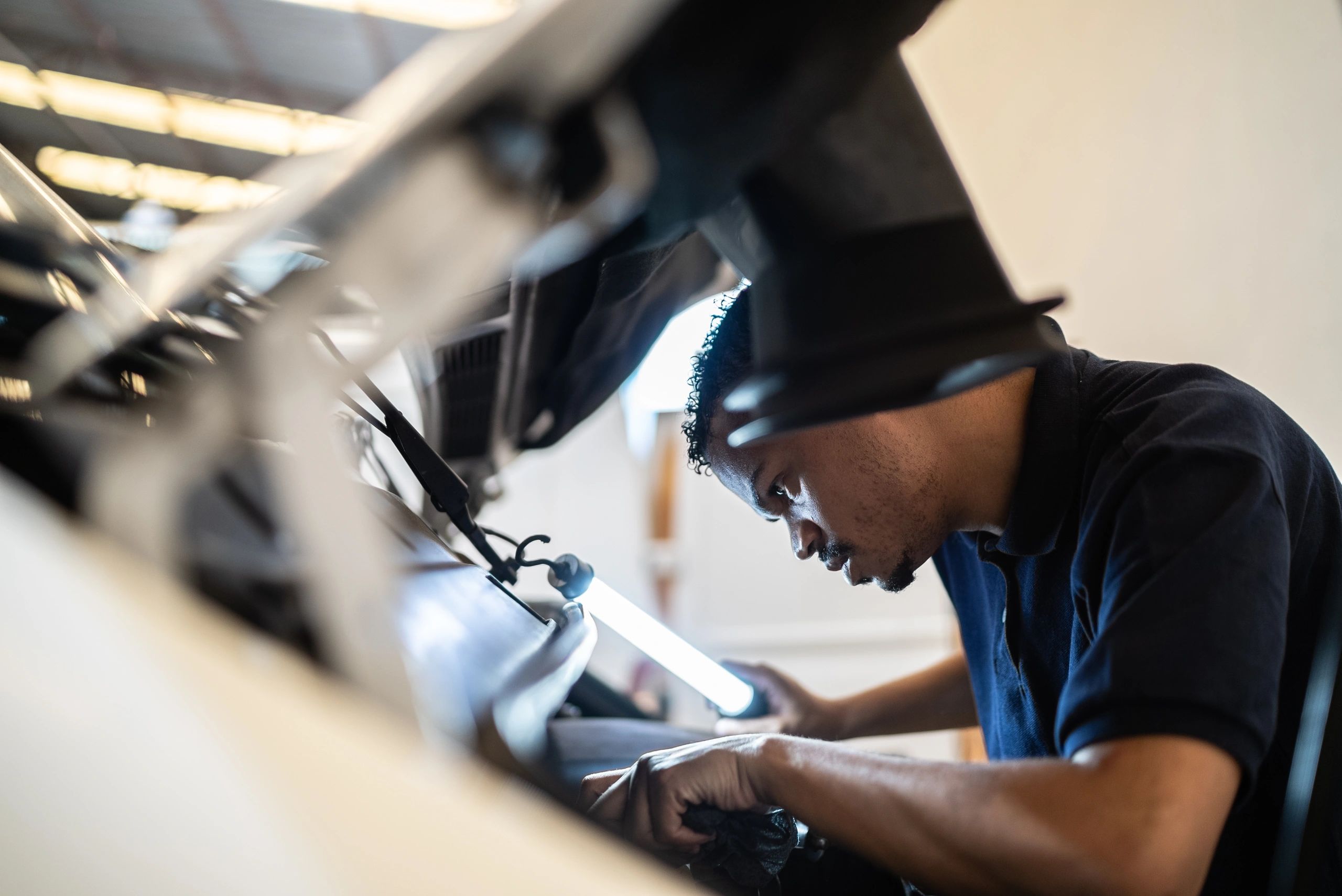 Technician working under the hood at an auto repair shop