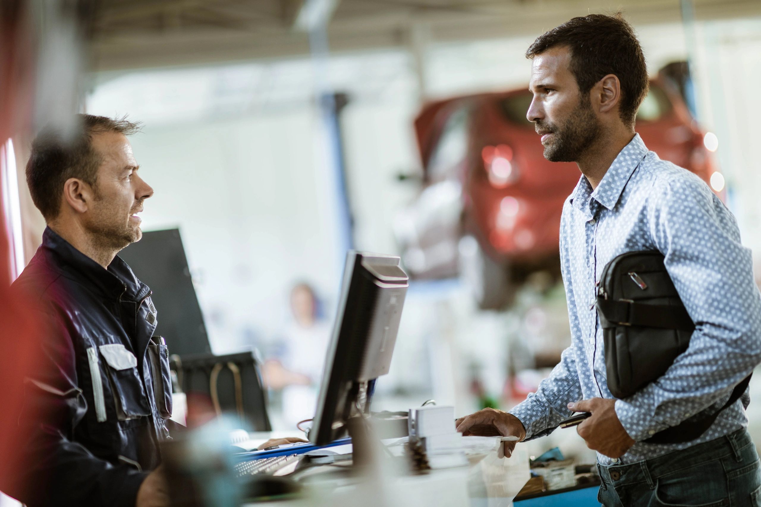 Customer speaking with a mechanic at an auto repair shop reception